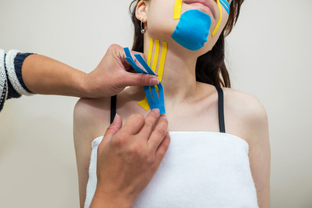 Kinesio taping. The physiotherapist applies kinesiology tape to the patient's neck. Post traumatic rehabilitation